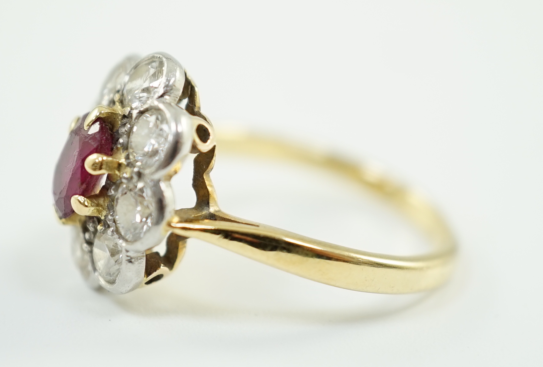 An 18ct gold, claw set single stone ruby and eight stone collet set diamond oval cluster ring